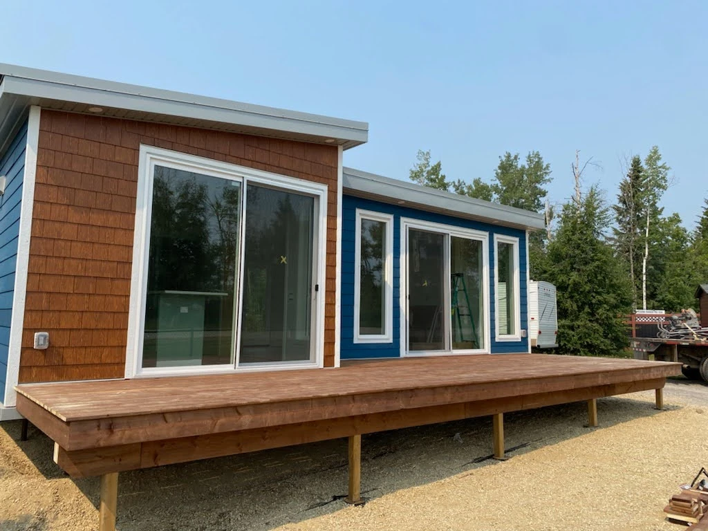 Modular home with wooden deck, wooden siding, and blue siding